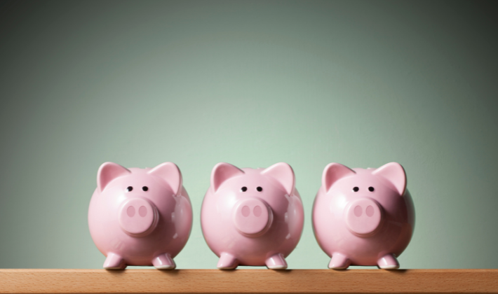 机の上に3つ並んだぶたの貯金箱の写真。収入を分散して心が折れにくくなる働き方を象徴するイメージ。